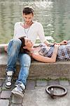 Woman lying on lap of a man at the ledge of a canal, Paris, Ile-de-France, France