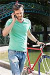 Man walking with a bicycle and talking on a mobile phone, Paris, Ile-de-France, France