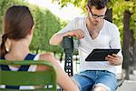 Man using a digital tablet with a woman sitting in front of him, Jardin des Tuileries, Paris, Ile-de-France, France