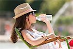 Woman sitting in a chair and drinking water, Bassin octogonal, Jardin des Tuileries, Paris, Ile-de-France, France