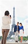 Woman taking a picture of couple with the Eiffel Tower in the background, Paris, Ile-de-France, France
