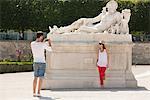 Homme qui prend une photo d'une femme debout près d'une sculpture dans un jardin, Jardin des Tuileries, Paris, Ile-de-France, France