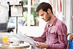 Man sitting at a sidewalk cafe and reading a map, Paris, Ile-de-France, France