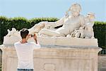 Man taking a picture of a sculpture in a garden, Jardin des Tuileries, Paris, Ile-de-France, France
