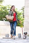 Woman holding a puppy on leash while talking on a mobile phone, Paris, Ile-de-France, France