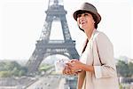 Woman holding a guide book with the Eiffel Tower in the background, Paris, Ile-de-France, France