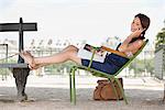 Femme allongée sur une chaise et parler sur un téléphone mobile, le Jardin des Tuileries, Paris, Ile-de-France, France