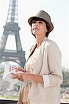 Woman holding a guide book with the Eiffel Tower in the background, Paris, Ile-de-France, France