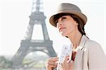 Woman holding a guide book with the Eiffel Tower in the background, Paris, Ile-de-France, France