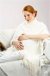 Portrait of a pregnant young woman sitting on a couch and smiling