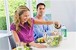 Woman pouring salad oil in salad and smiling