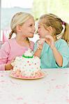 Two girls smiling in front of a birthday cake