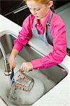 High angle view of a girl washing a measuring jug at a sink