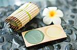 Close-up of a bar of soap with a flower and a tray of mud pack