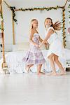 Two flower girls playing in a bedroom