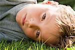 Boy lying on grass and looking serious