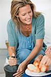 Woman using mortar and pestle with a person chopping onions