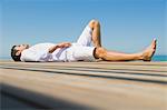 Homme étendu sur un trottoir de bois sur la plage