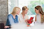 Woman sitting with her friends in a restaurant and looking into her wallet