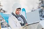 Jeune femme avec ordinateur portable dans la neige