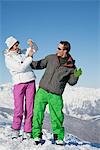 Young woman in ski wear taking a photo of her boyfriend