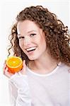 Portrait of a woman holding a half of an orange and laughing