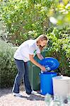 Woman throwing water bottles in garbage bin