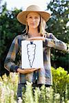 Portrait of a young woman showing carrot painting in a field