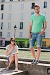 Couple on a ledge of a canal, Canal St Martin, Paris, Ile-de-France, France