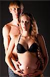 pregnant woman and her man on black background