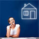 woman is sitting at table and thinking about a house