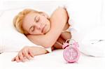 Young woman sleeping in the bed, alarm clock in the front