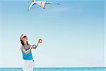 Young cute woman playing with a colorful kite on the tropical beach.