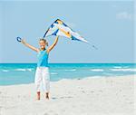 Young cute girl playing with a colorful kite on the tropical beach.