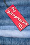 Red Russian Sale Sign With Stack of Blue Jeans in Background