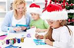 Family making seasonal greeting cards together at christmas time