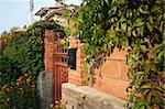 Cottage garden gates with brick wall and lot of plants