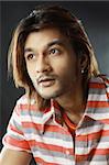 Close-up shot of a attractive young Indian male with long brown hair looking away.