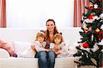 Portrait of mother with two twins daughters near Christmas tree