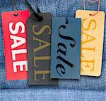 Tags With Sale Sign With Stack of Blue Jeans in Background