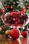 Christmas ornaments on table in front of holiday tree