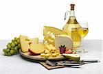 Composition of cheese, grapes, bottles and glasses of wine and strawberries on a wooden round tray on a white tablecloth, isolated on a white background