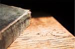 Leather covered old bible lying on a wooden table in a beam of sunlight Shallow Depth of field â?? Focus on Text â??Holy Bibleâ?