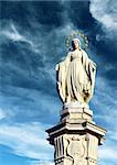 figure of the Madonna on a pedestal in the crown of gold, against a blue cloudy sky