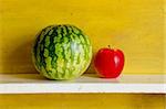 Watermelon and red apple on shelf. Healthy natural fruit food.