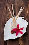 Red Tropical Plumeria Frangipani with Aromatherapy Oil and Cinnamon Stick on wooden table for spa and wellness concept