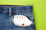 Royal flush with playing cards in blue jeans pocket with green background