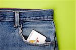 Joker playing card in blue jeans pocket with green background