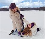 Woman and little girl having fun in the snow on a beautiful winter day