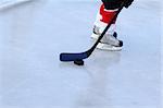 Young child playing ice hockey on a pond